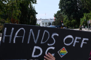 A 'Hands Off DC' poster in front of the White House