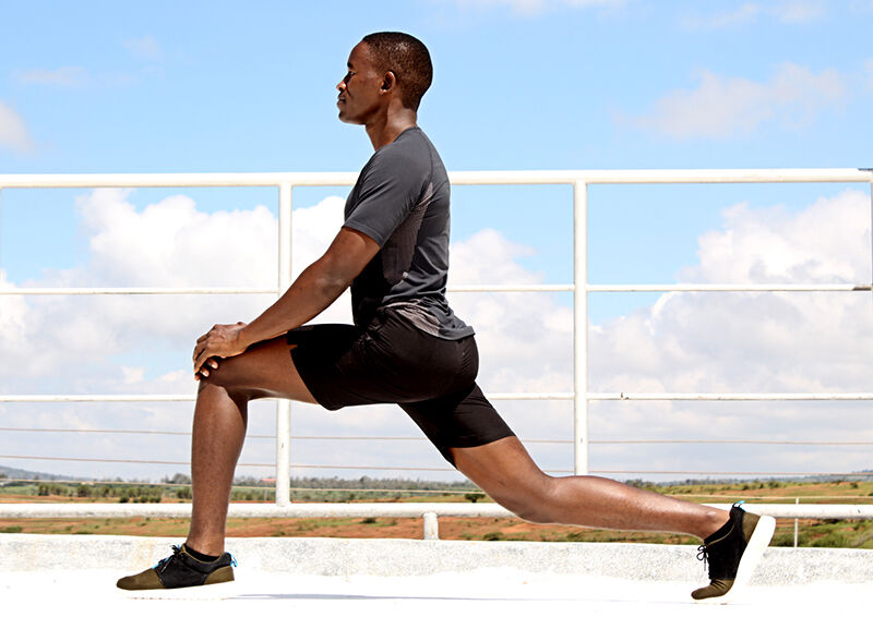 Young Fit Man Stretching Outside in Forward Lunge Position