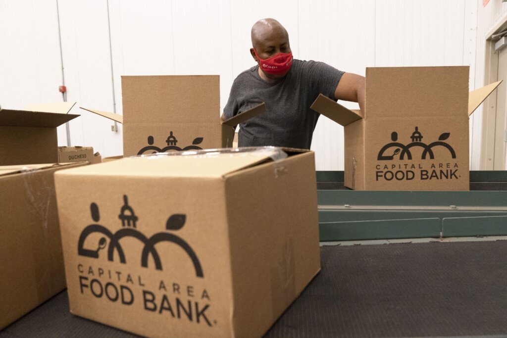 A volunteer pack boxes of food for distribution