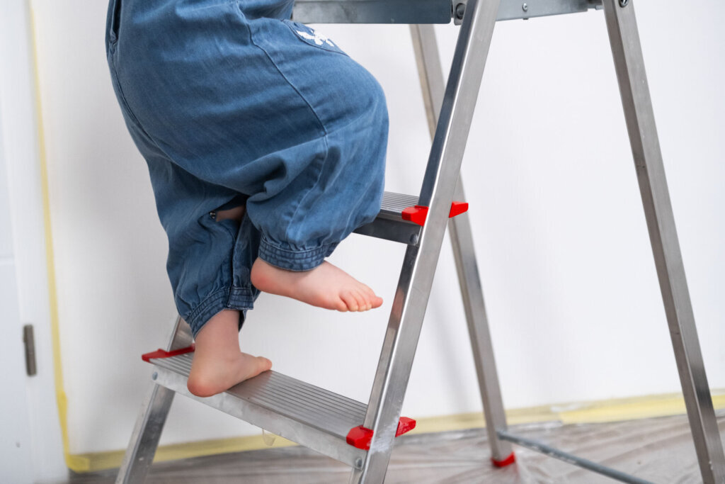 Close up of girls little legs and feet as she climbs a ladder indoors