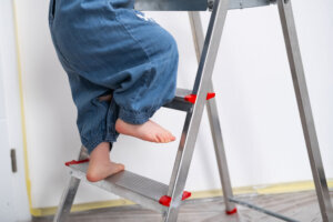Close up of girls little legs and feet as she climbs a ladder indoors
