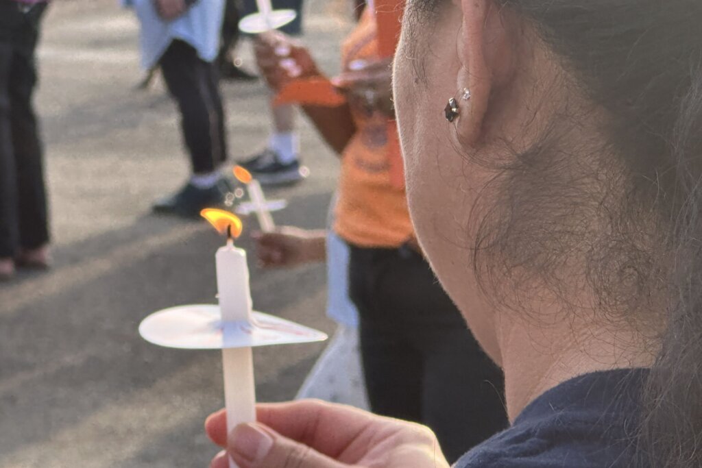 A woman holds candle at vigil