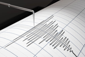 Printer head of an earthquake detector is oscillating, plotting high frequency pulse wave curves on graph paper. Illustration of the concept of tremor detection