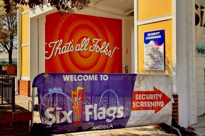 Visitors passing a sign quoting Porky the Pig as they leave Six Flags America
