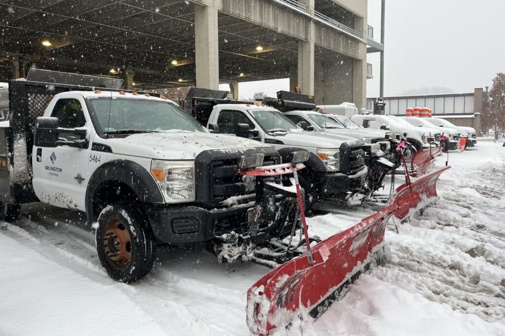 Parked snow plow trucks with snow on the ground