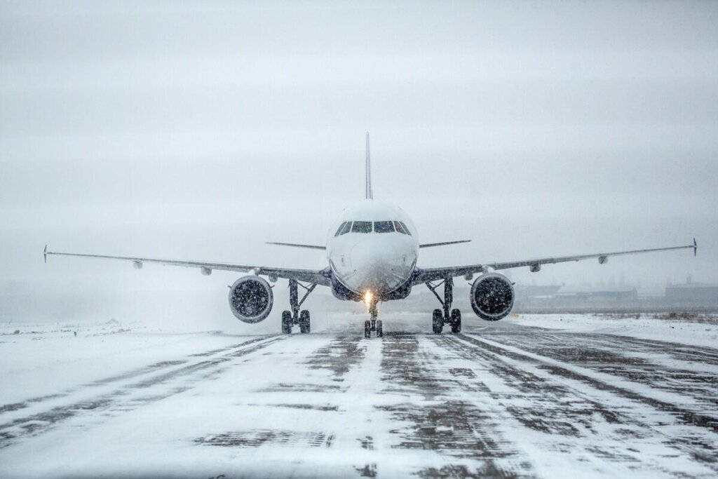 Airliner on runway in blizzard. Aircraft during taxiing during heavy snow. Passenger plane in snow at airport. Modern twin engine passenger airplane taxiing for take off at airport during snow blizzard