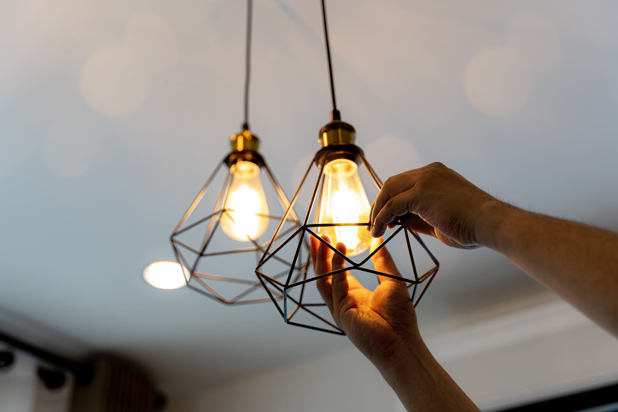 An electrician installing light bulbs on the ceiling inside a home