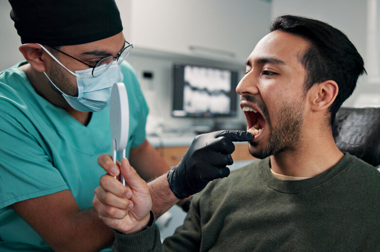 Dentist checks a man's mouth for oral treatment