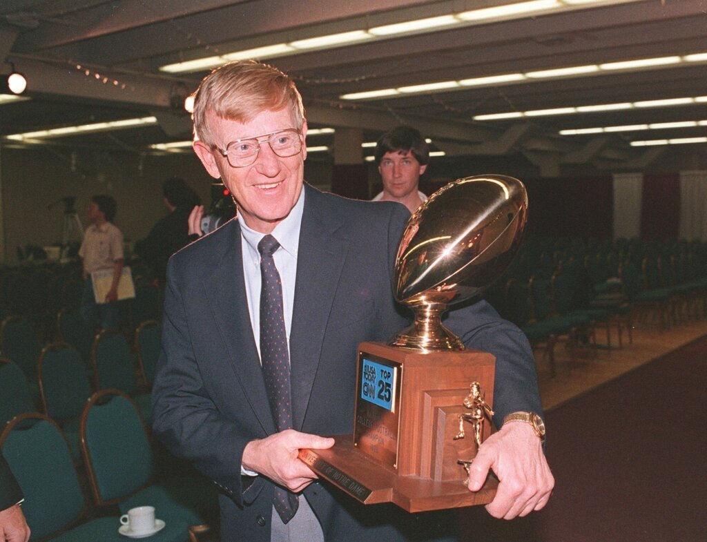 FILE - Notre Dame head coach Lou Holtz carries away the National College Champion Trophy following a news conference in Tempe, Ariz. in this Jan. 3, 1989 photo. Holtz died Wednesday, March 4, 2026. (AP Photo/Rob Schmacher, File)

&nbsp;