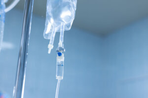 Close up of IV infusion system with clear fluid bag in a hospital setting