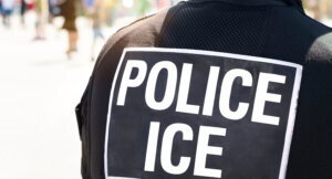 Ice Police Immigration and Customs Enforcement Close up of POLICE ICE marking on the back of a hi visibility stab proof vest worn by a police officer at the scene of an incident.