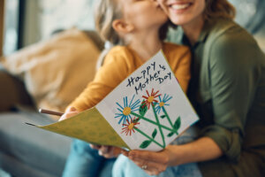 Close up of woman receiving Mother's day greeting card from her daughter.