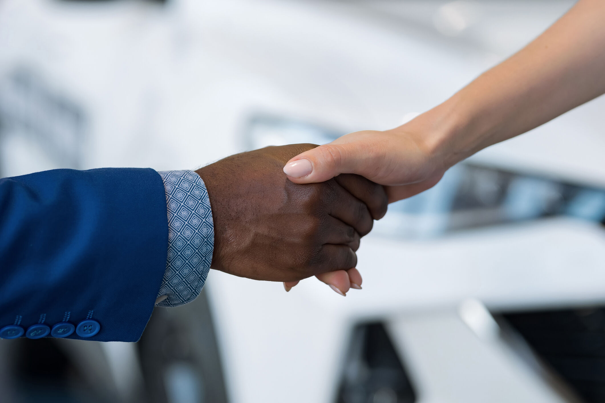 Salesman and female customer shake hands and pass car key