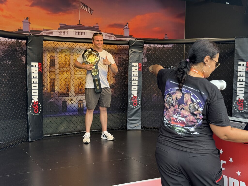 A man posing with a UFC championship belt. (WTOP/Jimmy Alexander)