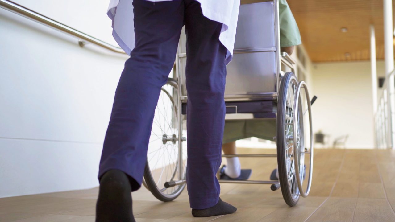 An elderly Asian patient and a doctor using a wheelchair