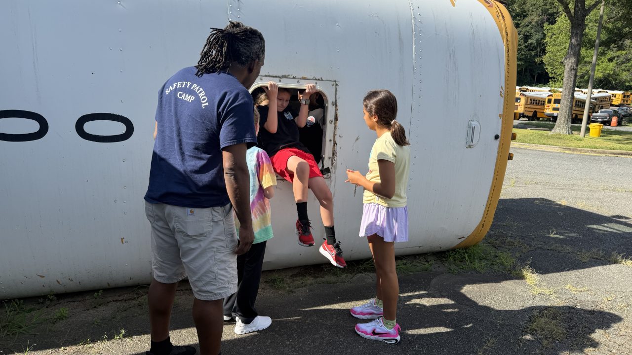 Kids emerge from an opening on the roof of an overturned school bus